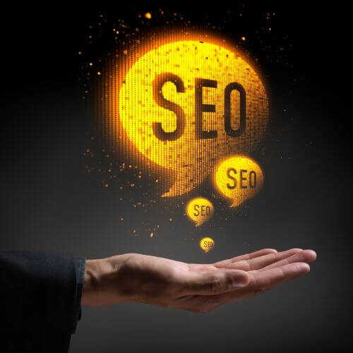 A text bubble with SEO in it floating above a hand.