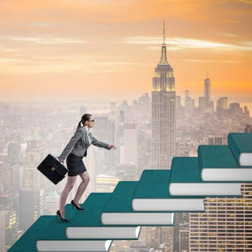 Business woman holding briefcase while climbing a stack of books